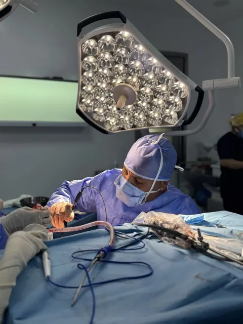 Chirurgien en blouse stérile au travail, scialytique et instruments chirurgicaux