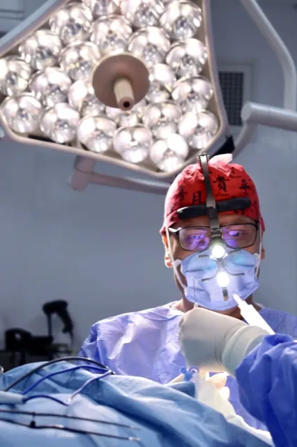 Surgeon wearing loupes and a headlight under the operating theatre light