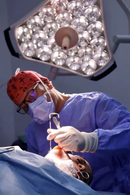 Surgeon focused on the operative gesture, surgical loupes and theatre lighting